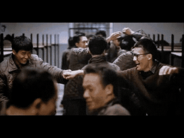 a group of people are standing in a room with their arms around each other and one of them is wearing glasses