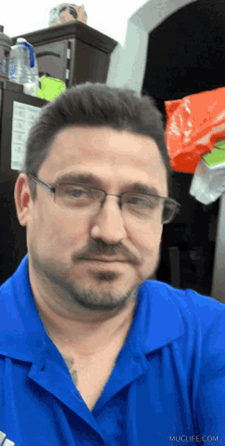 a man wearing glasses and a blue shirt has muglife.com written on the bottom right