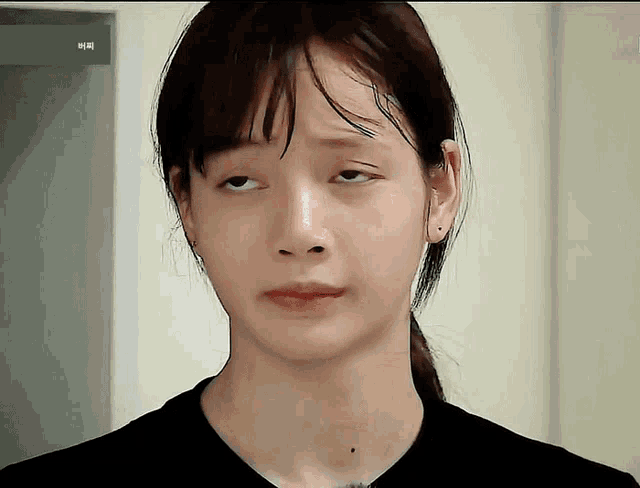 a close up of a woman 's face with a ponytail and a black shirt on