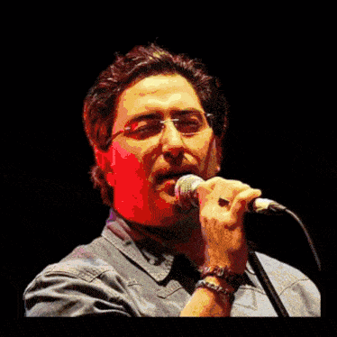 a man singing into a microphone in front of a sign that says the wall