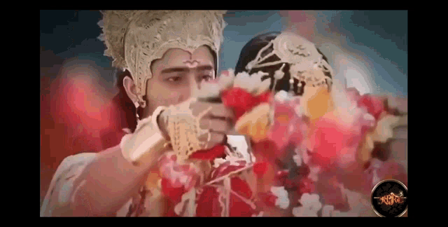 a man in a crown is holding a bow and arrow in front of a woman holding flowers .
