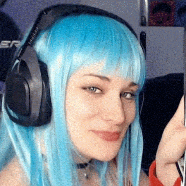 a woman with blue hair and headphones is smiling .