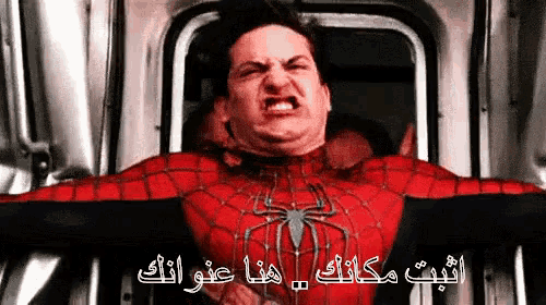 a man in a spiderman costume is making a funny face with arabic writing behind him