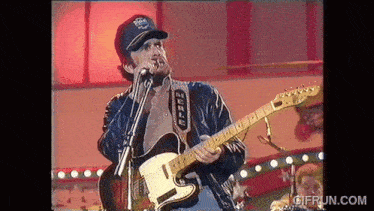 a man singing into a microphone while playing a guitar with merle written on the strap