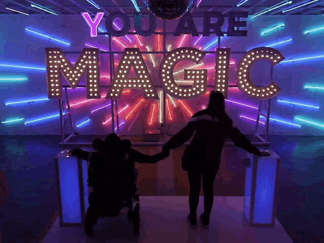 a couple holding hands in front of a sign that says you are magic