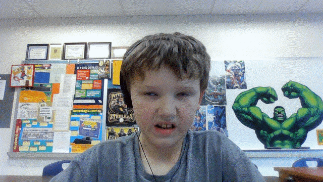 a boy wearing headphones stands in front of a bulletin board with a poster of the hulk