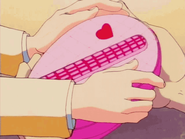 a person is holding a pink bento box with a heart shaped design on it