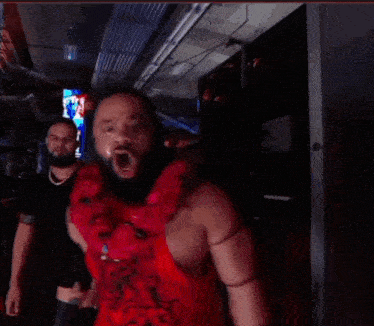 a man with a beard is wearing a red tank top with a dragon design