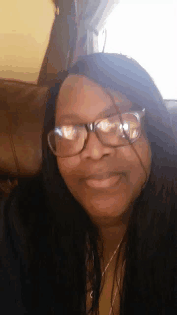 a woman wearing glasses is sitting on a couch
