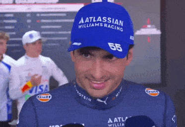 a man wearing a blue hat that says atlassian williams racing