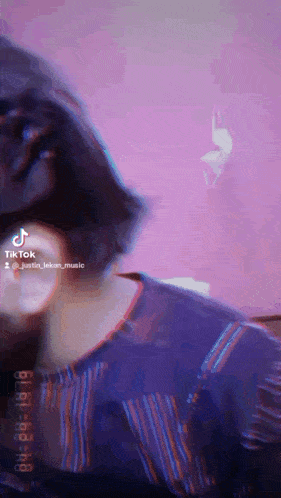 a tiktok video of a person with short hair and a purple background