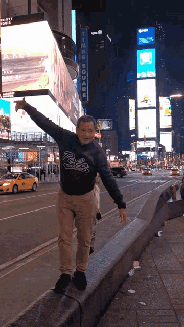 a boy wearing a polo sweatshirt stands on a curb