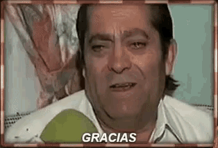a man in a white shirt is crying and the word gracias is on the bottom of the screen .
