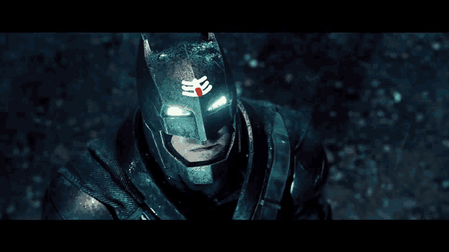 a close up of a man wearing a batman mask with a symbol on it