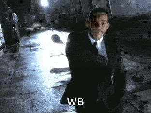 a man in a suit and tie is walking down a street with the word wb written on the bottom