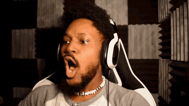 a man wearing headphones is sitting in a chair with his mouth wide open