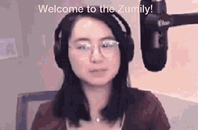 a woman wearing headphones and glasses is sitting in front of a microphone and says welcome to the zumily .