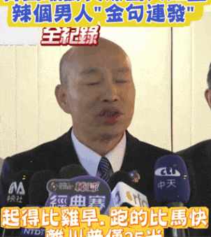a man in a suit and tie stands in front of a microphone with chinese writing on it