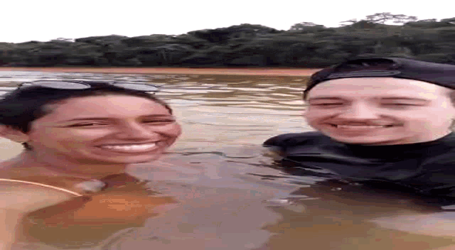 a man and a woman are standing in the water and smiling .