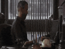 a man is sitting at a desk in front of a computer and writing on a piece of paper .
