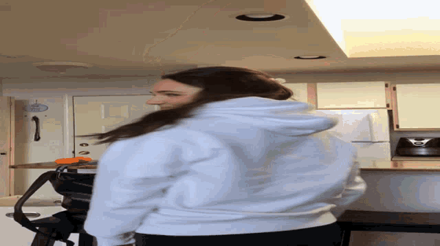 a woman in a white hoodie is standing in front of a refrigerator