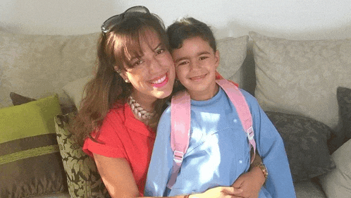 a woman in a red shirt is holding a little girl in a blue shirt