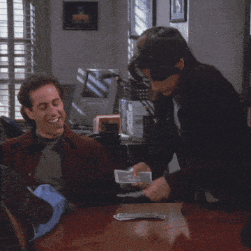 a man is smoking a cigar and smiling while another man holds a dollar bill