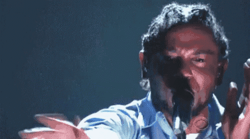 a close up of a man singing into a microphone .