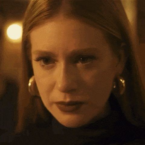 a close up of a woman 's face wearing hoop earrings and a black turtleneck .
