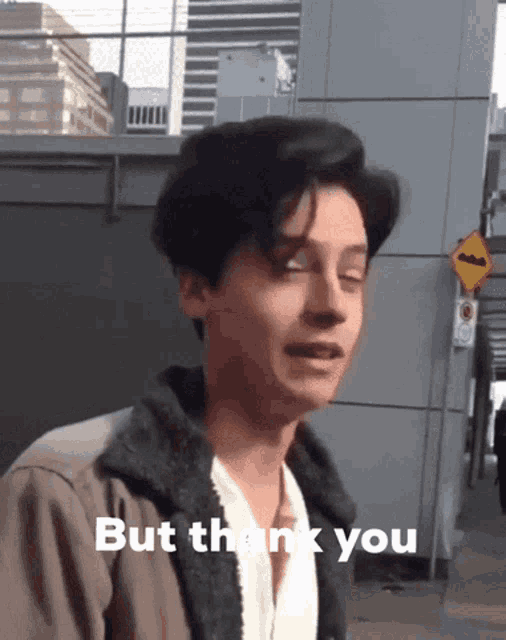 a man in a jacket says but thank you in front of a building