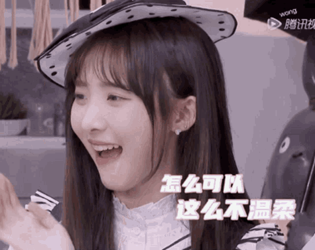 a girl wearing a polka dot hat is smiling with chinese characters behind her