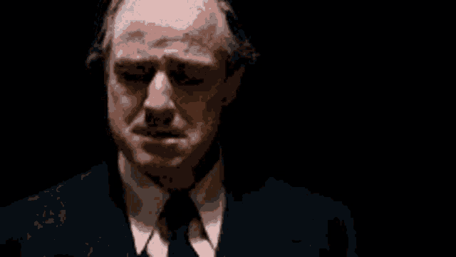 a man in a suit and tie is crying in a dark room