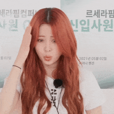 a woman with red hair is making a funny face in front of a sign that says 2021