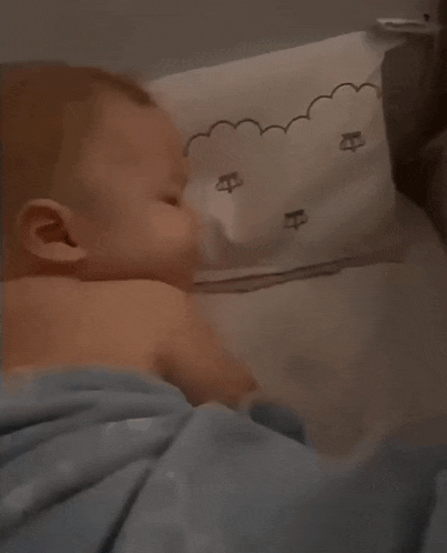 a baby is laying on a bed with a blue blanket on it