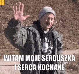 a man wearing a hat and a jacket is waving his hand