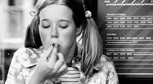 a black and white photo of a young girl applying makeup .