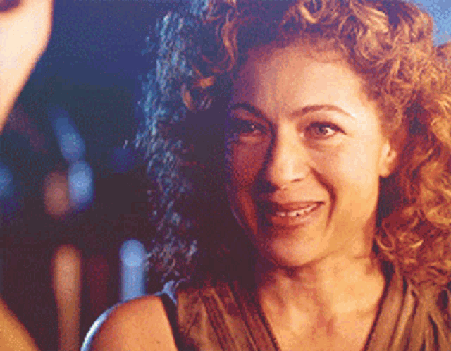 a woman with curly hair is smiling at someone