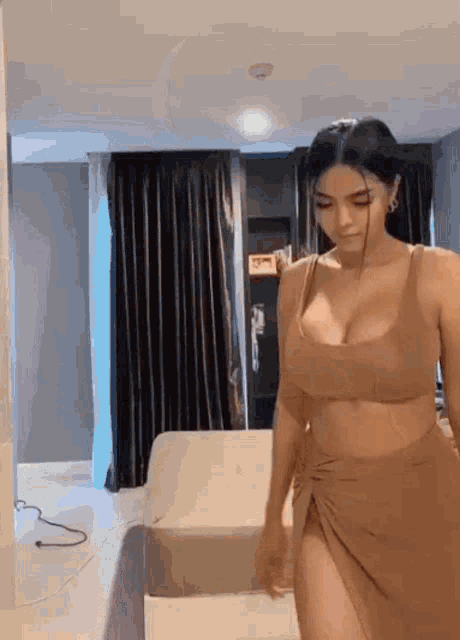 a woman in a brown dress is walking in a room