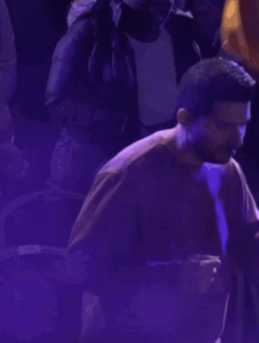 a man with a beard is dancing in a crowd of people .