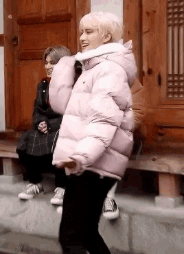 a person wearing a pink jacket is standing in front of a building