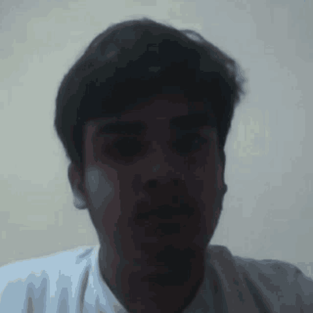 a young man with a white shirt on looks at the camera