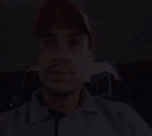 a man wearing a red hat and a grey shirt is sitting in the back seat of a car