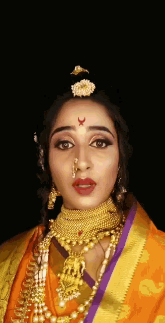 a woman with a nose ring and gold jewelry on her face