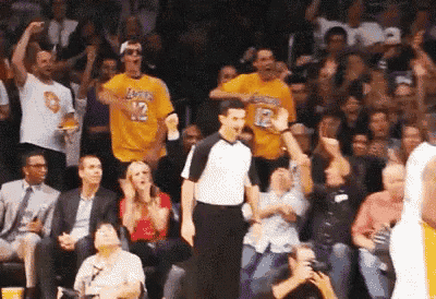 a referee is standing in front of a crowd wearing a lakers shirt