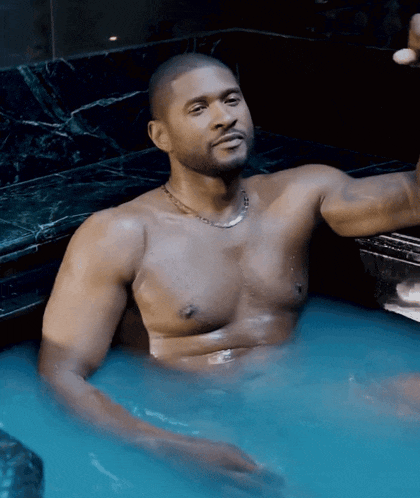 a shirtless man laying in a bathtub with blue water