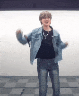 a man in a denim jacket is dancing in a room .