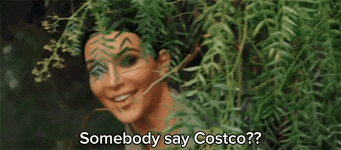 a woman is peeking out from behind a tree and smiling while saying somebody say costco ?