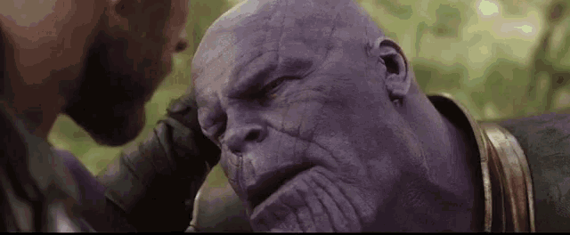 a man is putting his hand on the head of a purple superhero .