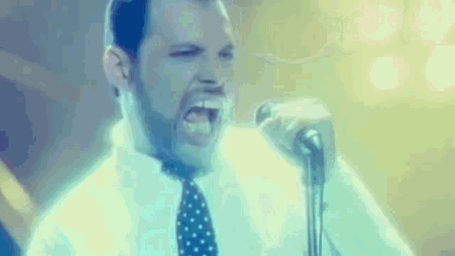 a man singing into a microphone in a white shirt and tie