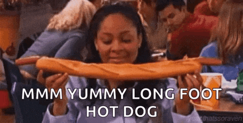 a woman is eating a very long hot dog .